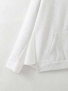 Close-up of light gray hoodie fabric with white shirt hem splicing detail