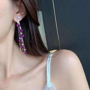 Detail of purple rose tassel earrings with shimmering crystals on long gold chains