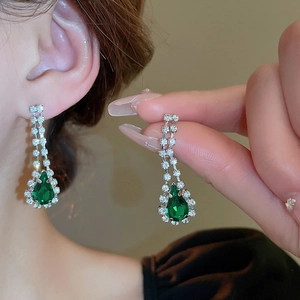 Detail of silver drop earrings with green pear-shaped gemstones and sparkling crystals