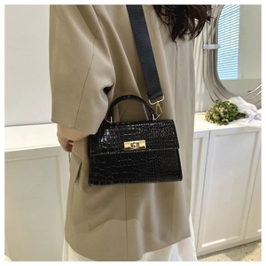 Detail of black crocodile texture handbag with gold twist lock and wide shoulder strap