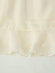Dettaglio macro dell'orlo con volant sull'elegante set gonna in chiffon beige