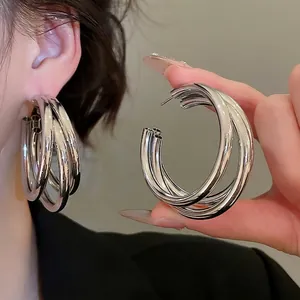 Polished silver layered triple hoop earrings featuring a minimalist industrial design