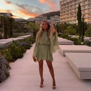Elegant sage green ruffled mini dress with tiered sleeves shown in a garden sunset scene
