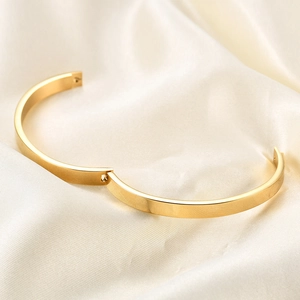 Polished 6mm gold stainless steel hinged bangle for women on minimalist silk background