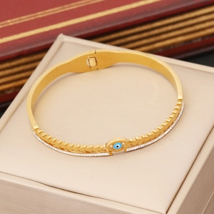 Macro detail of golden evil eye bangle with wheat spike engraving and white zircons