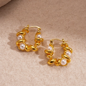 Vintage gouden gedraaide U-vormige oorbellen met parels op beige pluche achtergrond