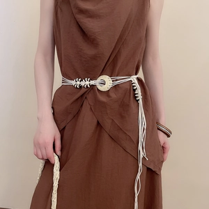 Detail of bohemian hand-woven waist chain with wooden buckle on a brown linen dress
