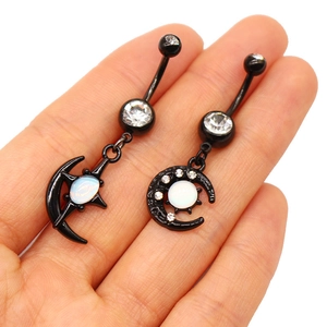 Détail de piercings de nombril noirs lune et étoile avec opale sur la paume de main