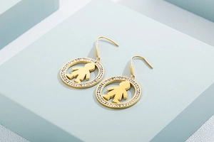 Detailed view of round gold earrings with micro-inlaid rhinestones and boy charm