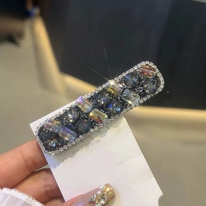 Close-up of sparkling dark grey crystal hair clip on a display card with rhinestones