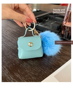 Detail of blue faux crocodile leather mini pouch keychain with fluffy pompom and gold clasp