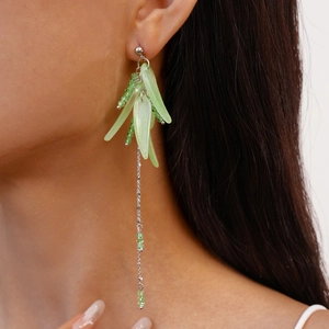 Close-up of elegant green leaf tassel earring with silver chain worn by a professional model