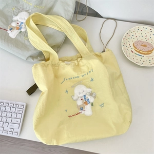 Detail of canvas shoulder bags featuring cute embroidered lamb and drawstring closure