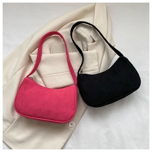 Detailed view of corduroy baguette shoulder bags in rose red and black on beige blazer