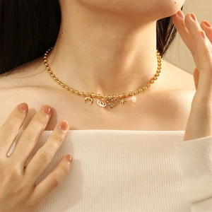 Exotic golden necklace with zircon and pearl charms worn by a model on a warm background