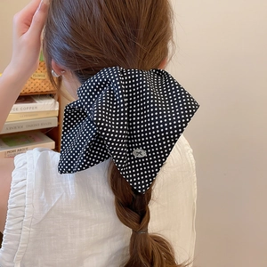Detailed view of large black polka dot scrunchie with bow on model ponytail braid