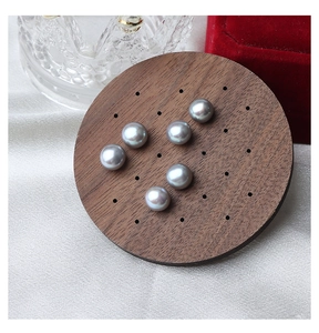 Macro detail of six grey-purple freshwater pearls on a round wooden display tray