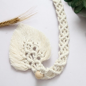 Detail of leaf-shaped hand-woven cotton curtain tieback with decorative wood bead