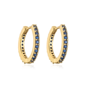 Close-up of golden hoop earrings with channel-set blue crystals in a minimalist design
