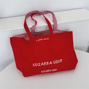 Detail der roten Canvas-Tasche mit weißer Bestickung und gestreiftem Innenfutter