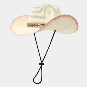 Détail d'un chapeau de paille beige style cowboy avec bords roses et ruban à motifs