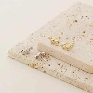 Macro shot of minimalist gold and silver S925 geometric bead stud earrings with crystals