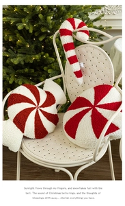 Close-up of red and white candy-shaped plush Christmas pillows on a white metal chair