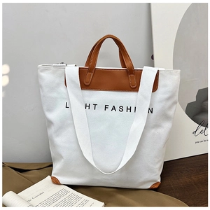 Detail of white canvas tote bag with brown leather handles and chic printed lettering