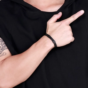 Detail eines schwarzen Herren-Mesh-Armbands aus Edelstahl an einem tätowierten Arm