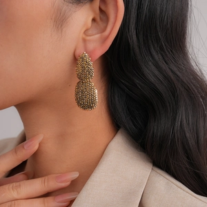 Gros plan détaillé de boucles d'oreilles goutte d'or texturées portées par un mannequin