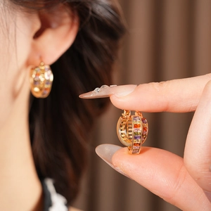 Close-up of vintage golden hoop earrings with colorful inlaid rectangular gemstones