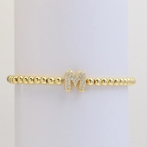 Close-up of golden beaded stretch bracelet with micro-paved zircon letter M pendant