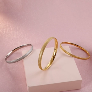 Three minimalist titanium steel bracelets in gold and silver with frosted texture finish