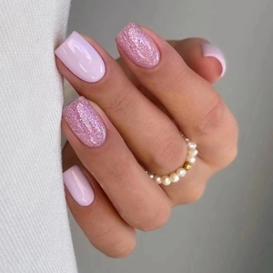 Macro detail of medium-long square round nails with pink glitter and solid glossy finish