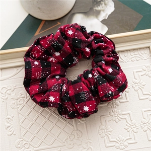 Detail of red and black plaid scrunchie with white snowflake print for festive hairstyles