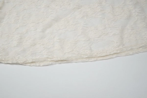 Close-up detail of cream white floral lace fabric and sheer mesh texture on the dress