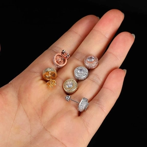 Detailed view of hand-held round zircon earrings in gold, silver, and rose gold finishes