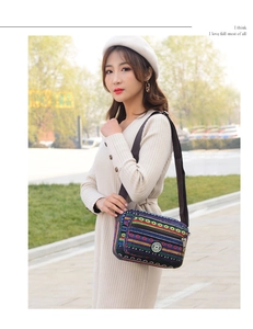 Ethnic style striped canvas crossbody bag with multiple zipper pockets on outdoor model