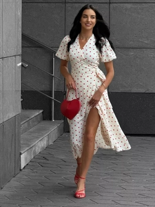 Detail of red heart print on white cotton wrap dress with a high side slit and tied waist