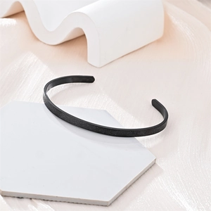 Vista detallada de un brazalete de acero de titanio en forma de C negro mate