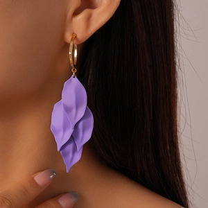 Gros plan de boucles d'oreilles pétales violets à plusieurs niveaux avec anneaux dorés