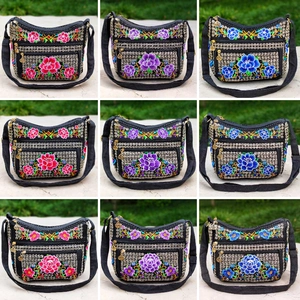 Detailed close-up showing vibrant peony floral embroidery and metal zipper pulls on bags