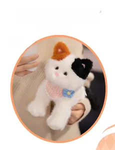 Close-up of calico cat plush toy with pink plaid bib and blue crochet flower detail