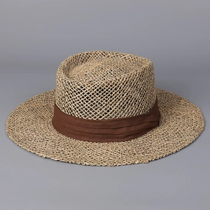 Close-up of wide-brim straw hat featuring hollow weave texture and brown fabric ribbon