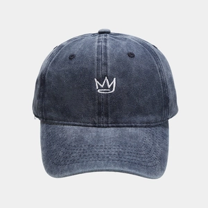 Detailed close-up of crown embroidery on vintage washed navy denim baseball cap