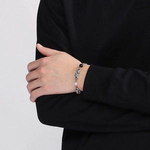 Detail of titanium steel chain bracelet with white pearl on person wearing black sleeve