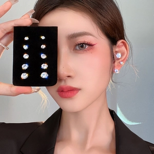 Detailed view of silver magnetic stud earrings set with multiple zircon sizes on model