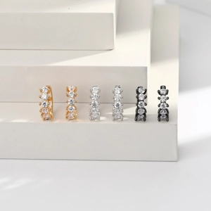 Macro view of geometric silver earrings in gold, silver, and black with five zircon stones