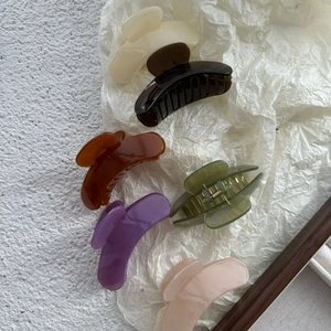 Detailed top view of 6 colorful matte jelly hair claws on a textured white paper background