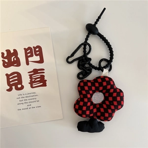 Detailed view of plush flower charm with red and black checkered pattern and plastic chain